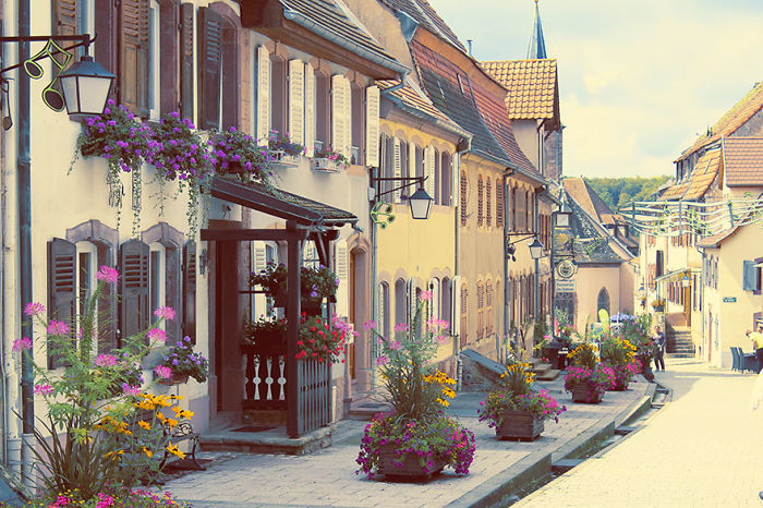 Charming fairy tale village street with colorful houses and vibrant flowers, evoking a magical, picturesque atmosphere.