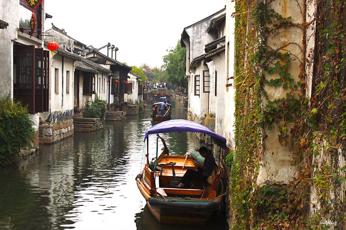 A scenic canal in a fairy tale village with a traditional boat and historic houses on either side.