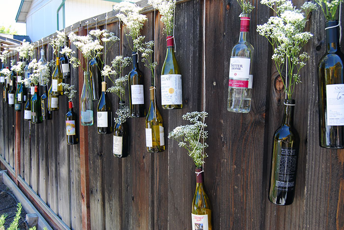 Wine Bottles Repurposed Into A Beautiful Vase Composition On A Fence