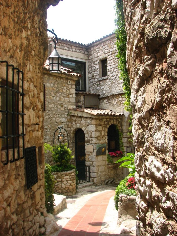 Charming stone alley in a fairy tale village, adorned with greenery and flowers.