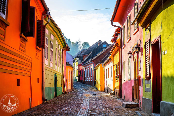 Colorful fairy tale village street with vibrant houses and cobblestone path, perfect for tourism and exploration.