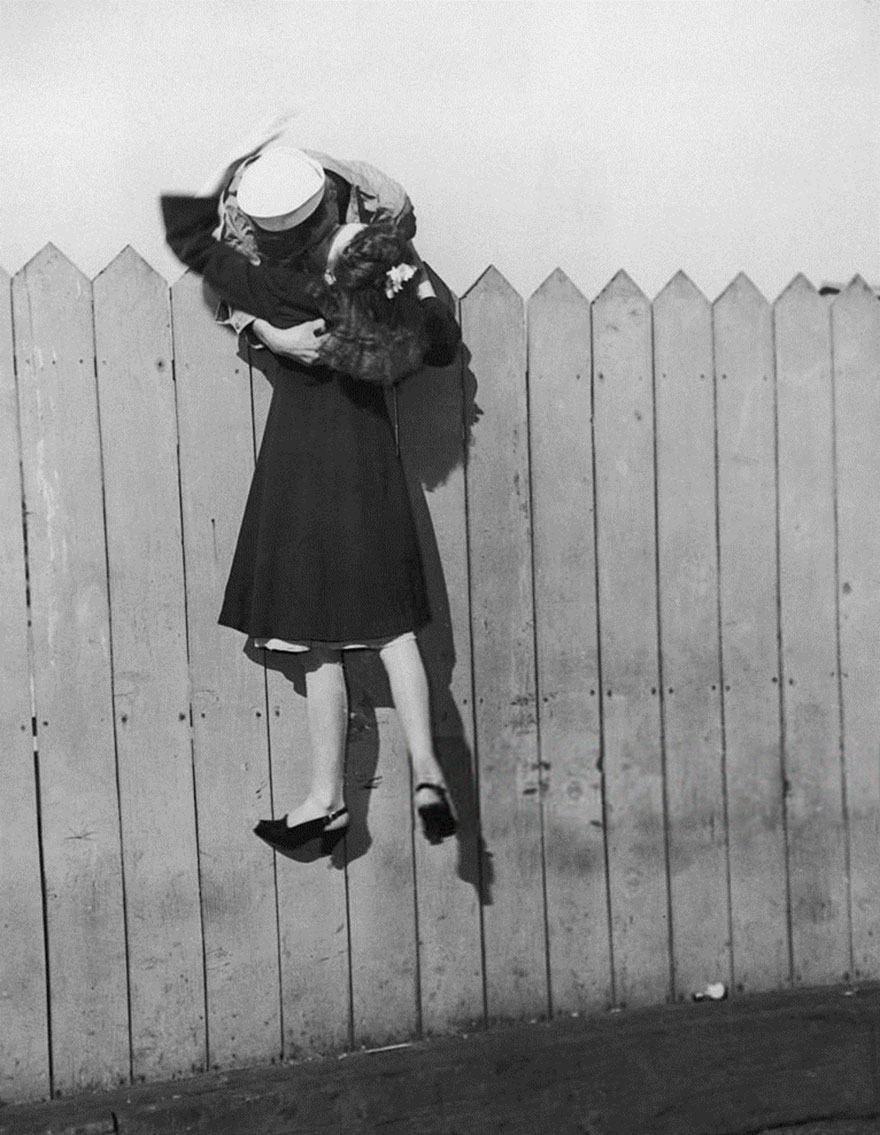 A Sailor Leans Over A Picket Fence And Lifts His Girlfriend Up For A Kiss, 1945