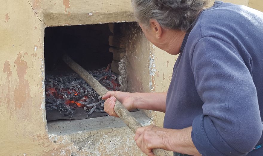 Grandmother Baking Bread In Outdoor Oven