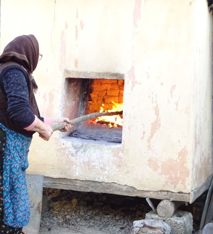 Grandmother Baking Bread In Outdoor Oven