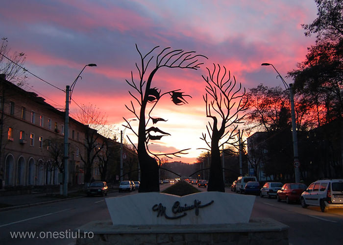 Metal sculpture of a face formed by tree-like branches on a street at sunset, an amazing sculpture in the world.