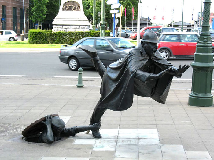 Bronze sculpture of a man slipping on the street while another figure pulls his leg, showcasing amazing sculptures in the world.