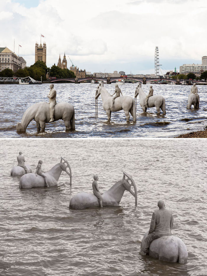 Sculptures of men riding horses partially submerged in river water with city landmarks in the background.