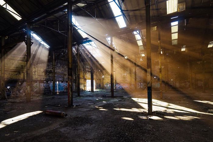 Sunlight beams through broken windows of an abandoned industrial building, showcasing decayed UK architecture and abandoned places.