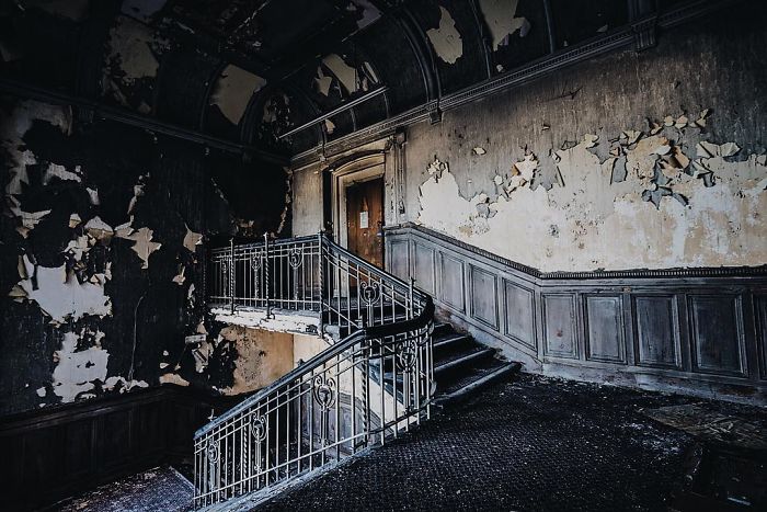 Interior of an abandoned building in Britain showing peeling walls and a worn staircase, capturing abandoned places atmosphere.