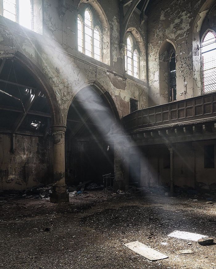 Sunlight streaming through broken windows in an abandoned Britain building, showcasing decay in historic UK abandoned places.