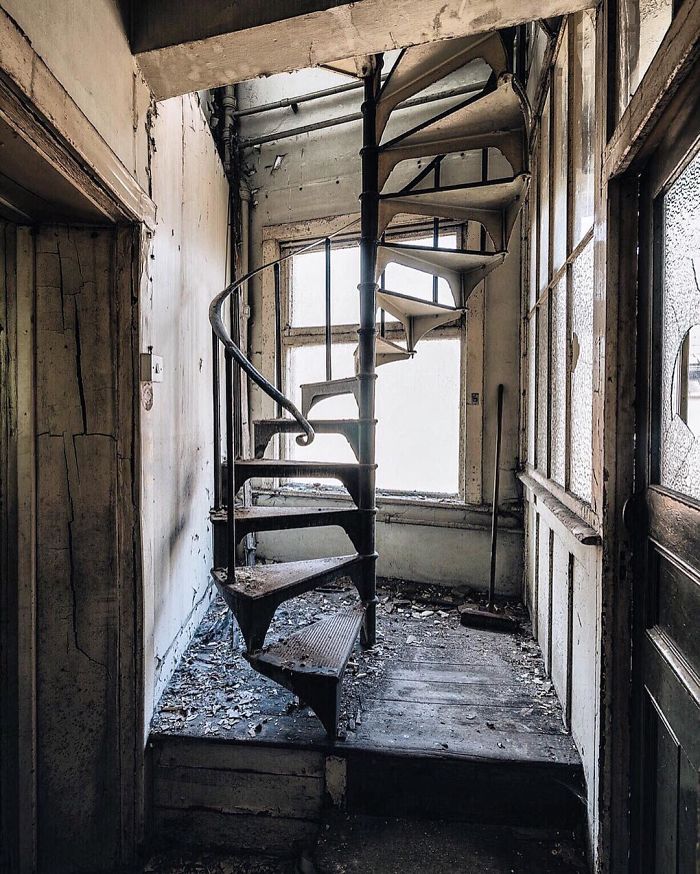 Spiral staircase in a decayed interior of an abandoned Britain building, showcasing the eerie charm of UK abandoned places.