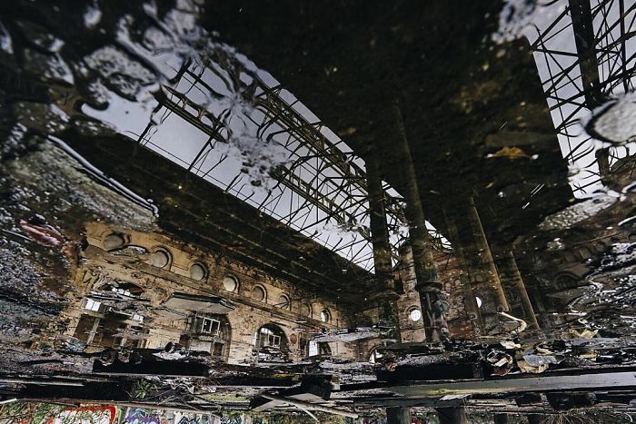 Reflection of an abandoned industrial building ruins in water, showcasing decay in abandoned Britain urban exploration.