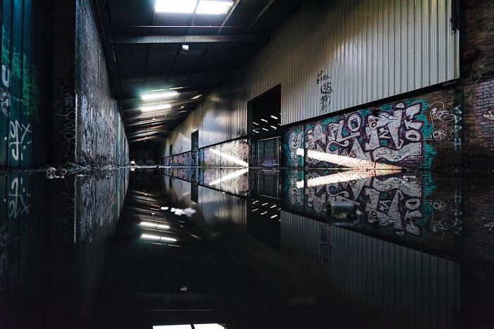 Abandoned Britain interior of flooded warehouse with graffiti-covered walls and reflections in water inside UK abandoned places.