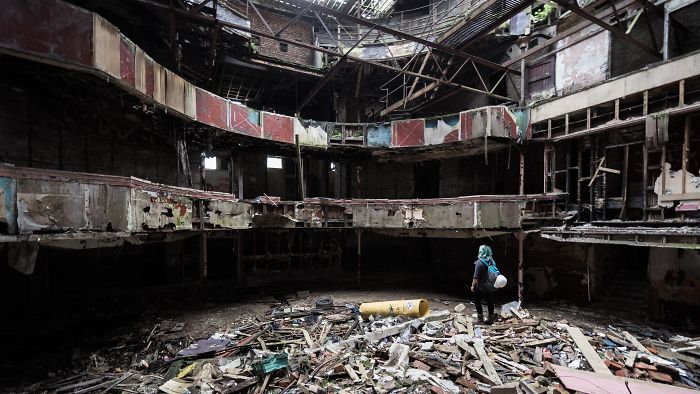 Person exploring a large abandoned place in Britain filled with debris and decaying structures inside a ruined building.