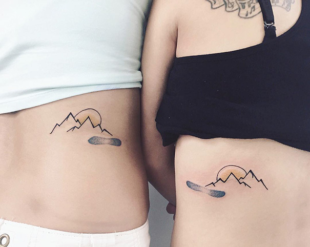 Two mountains and snowboard back tattoos 