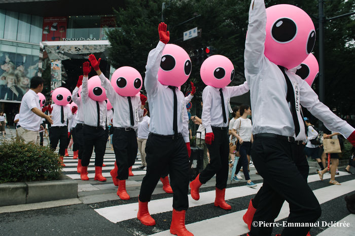 Group of people in pink alien masks and red boots crossing a street in Japan street photography scene.