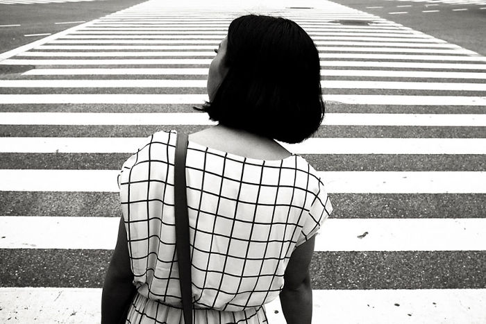 Woman crossing a street in Japan wearing a grid-patterned top, captured in black and white Japan street photography style.