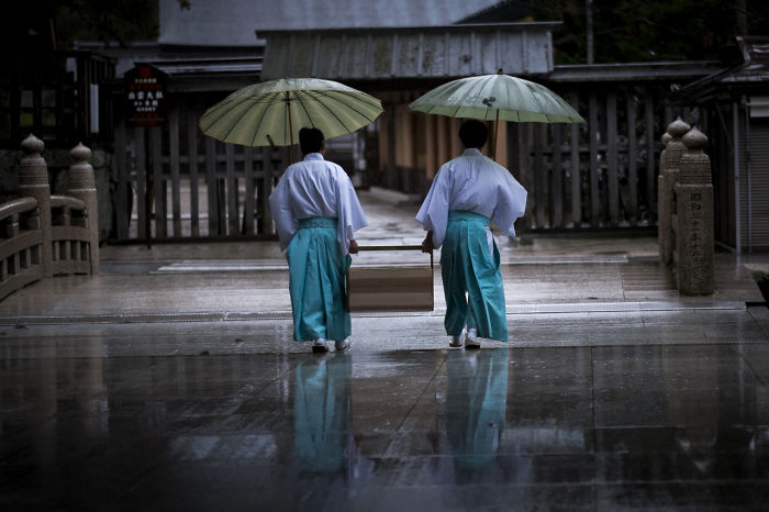 Two people in traditional clothing holding umbrellas on a wet street, showcasing Japan street photography in a rainy scene.