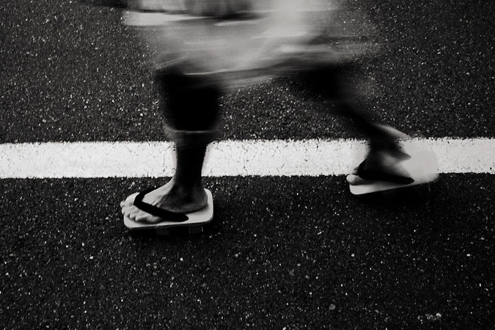 Blurred motion of person wearing traditional Japanese sandals walking on street in Japan street photography shot.