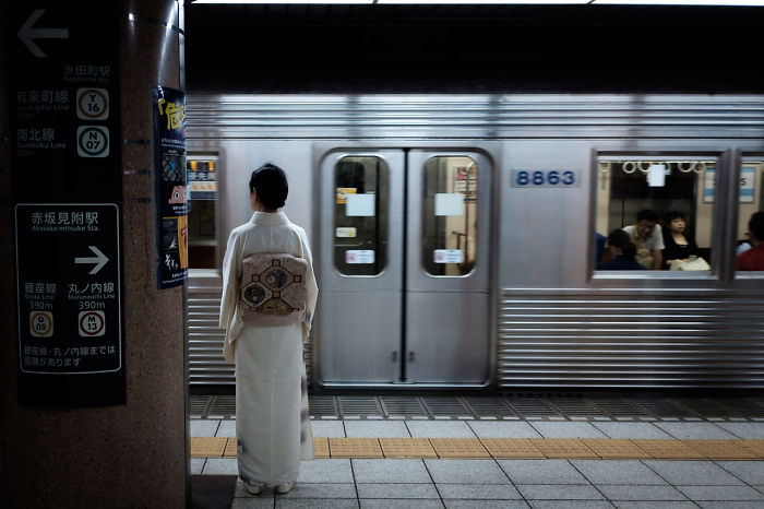 Woman in traditional kimono standing on subway platform in Japan street photography scene with passing train background