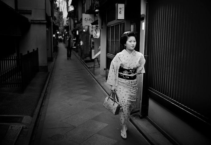 Japanese woman in traditional kimono walking down a narrow street, showcasing Japan street photography capturing unique moments.