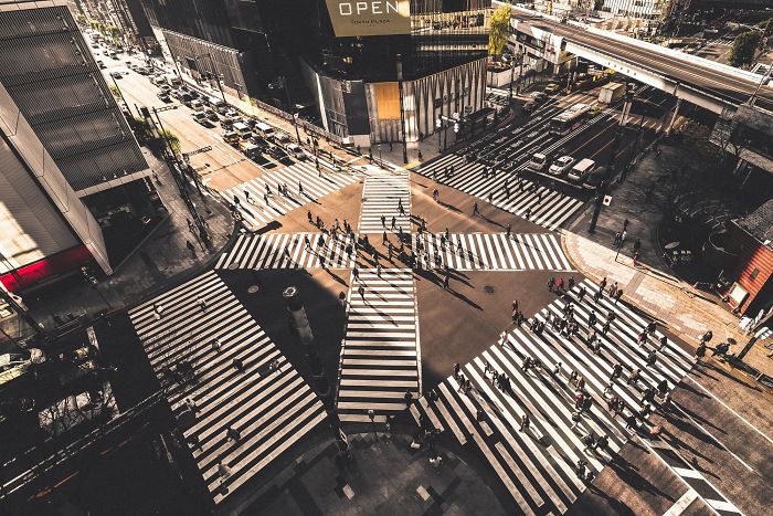 Aerial view of a busy urban crosswalk in Japan with pedestrians and shadows showcasing Japan street photography.
