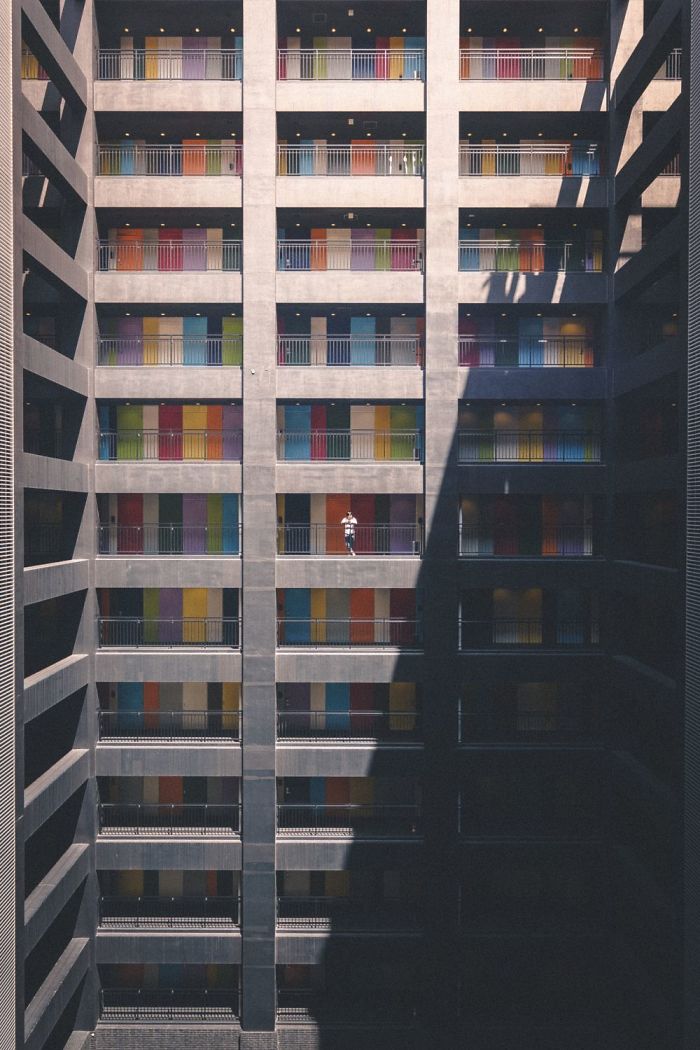 Colorful doors line the balconies of a tall apartment building in Japan, captured in striking Japan street photography style.