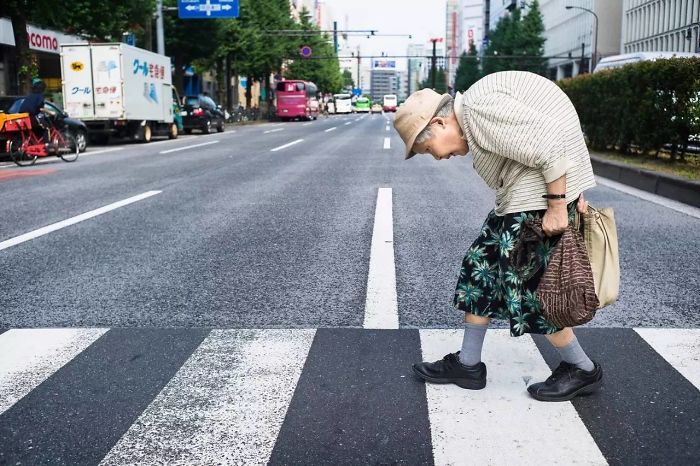 Elderly woman crossing a quiet street in Japan, capturing a unique moment of Japan street photography and daily life.