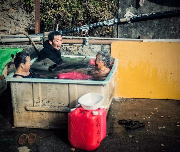 Three people enjoying a rustic outdoor bath, captured in Japan street photography showing local daily life moments.