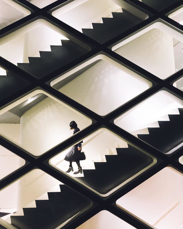 Abstract Japan street photography showing a person walking down modern geometric stairs in a minimalist setting.