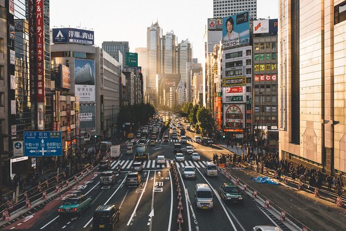Busy Japan street photography scene of urban traffic and high-rise buildings in golden sunlight on a clear day.