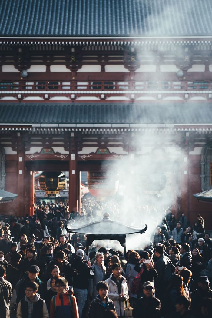 Crowd around incense burner at traditional temple showcasing Japan street photography in an urban cultural setting.