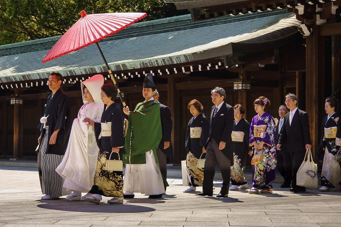 Traditional Japanese wedding procession with colorful kimonos and a red umbrella in Japan street photography shot.