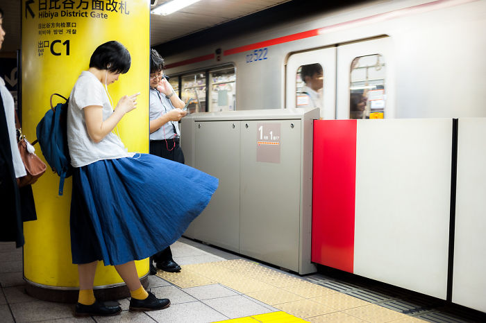 Woman in a blue skirt waiting at a Japan subway station captured in street photography of the Land of the Rising Sun