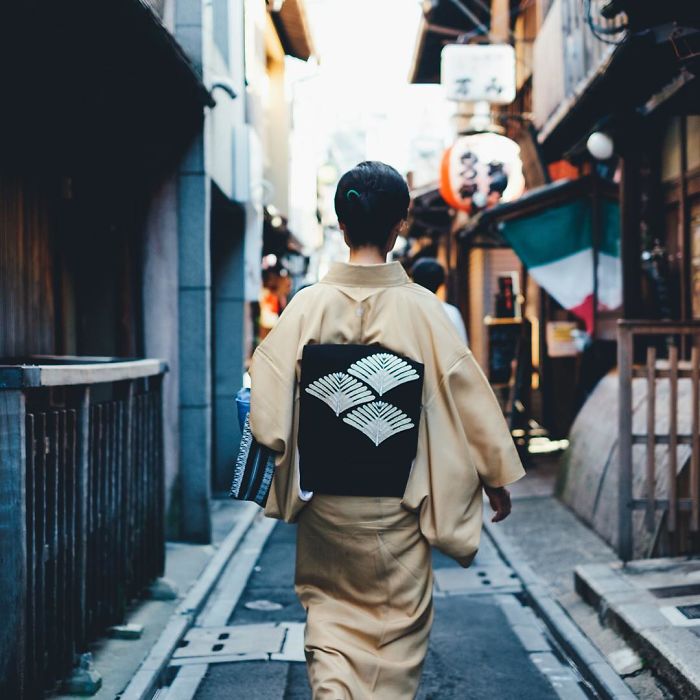 Woman in traditional kimono walking through narrow Japan street in authentic street photography capturing daily life scenes