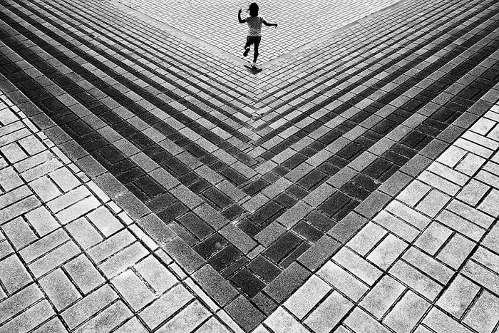 Child running on patterned pavement captured in Japan street photography showcasing unique urban perspective and patterns.