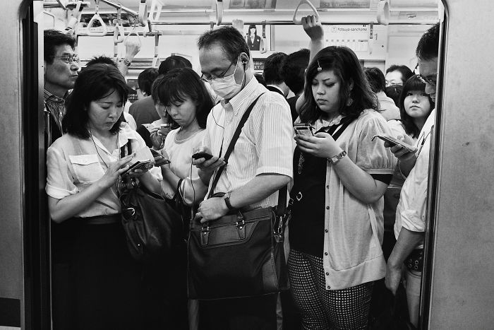 Crowded Japan train interior with commuters absorbed in their phones, an example of Japan street photography capturing daily life.