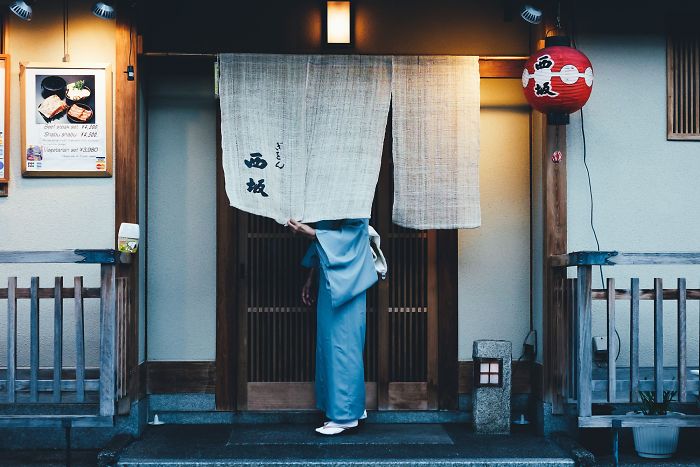 Person in traditional clothing entering a Japanese street scene, capturing rare Japan street photography moments.