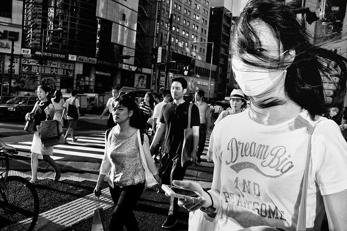 Black and white Japan street photography capturing candid moments of pedestrians in an urban setting with dynamic light and shadows.