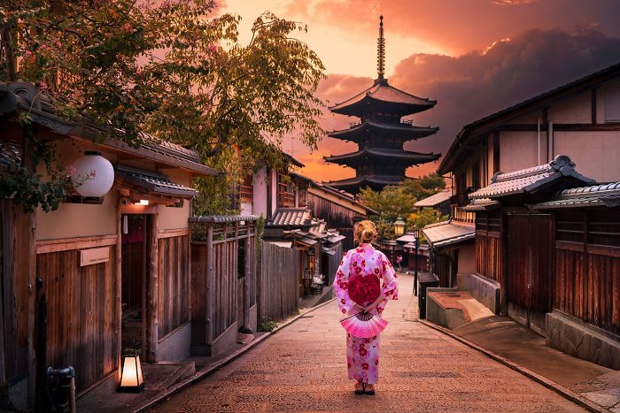 Woman in traditional kimono walking down a street in Japan at sunset, showcasing Japan street photography and culture.