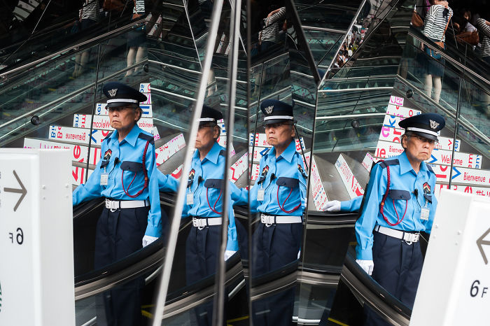 Japanese street photography showing a security guard reflected in multiple mirrors near an escalator in an urban setting.