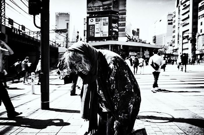 Black and white Japan street photography showing a person in a busy urban crosswalk capturing daily city life.