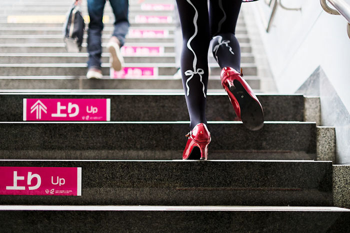 Person wearing red high heels and black tights walking up stairs in a Japan street photography shot capturing urban life.