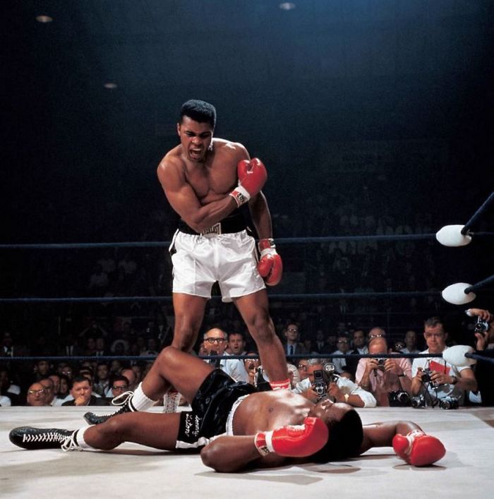 Boxer standing triumphantly over fallen opponent in iconic sports image.