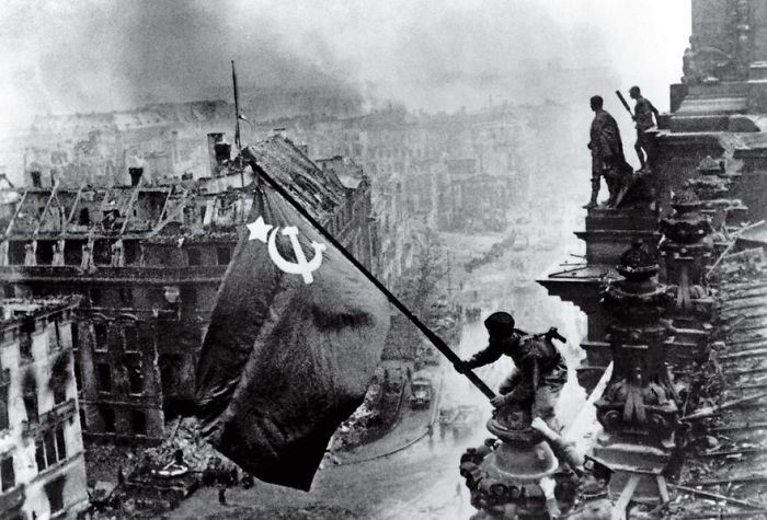 Soviet soldiers raise flag over Berlin, symbolizing victory in one of history's most famous photos.