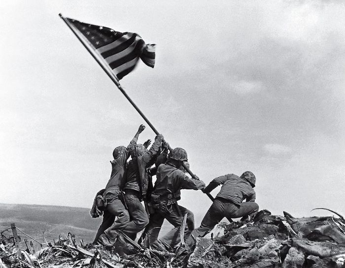 Soldiers raising the American flag on Iwo Jima during WWII, capturing a famous moment in history.