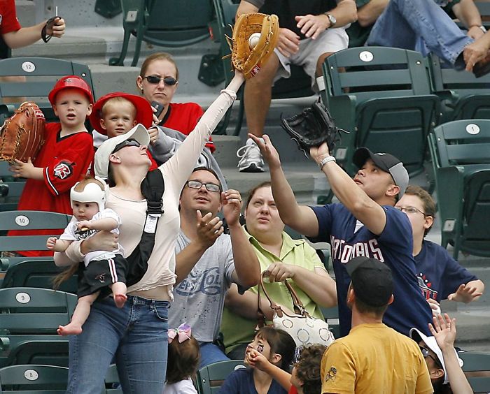 Mom With Baby Catches A Fly Ball At A Baseball Game