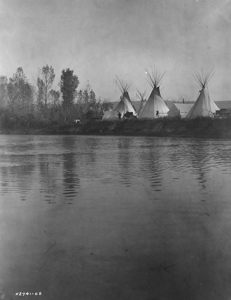 Crow Encampment With Tipis, Tents, Wagons, Horses And Men As Seen From The Distant Shore Of The River, 1908