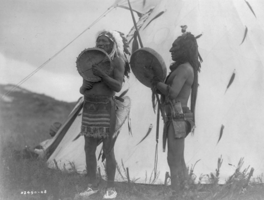 Two Dakota Men Playing Hand Drums Outside Of A Tipi, 1908
