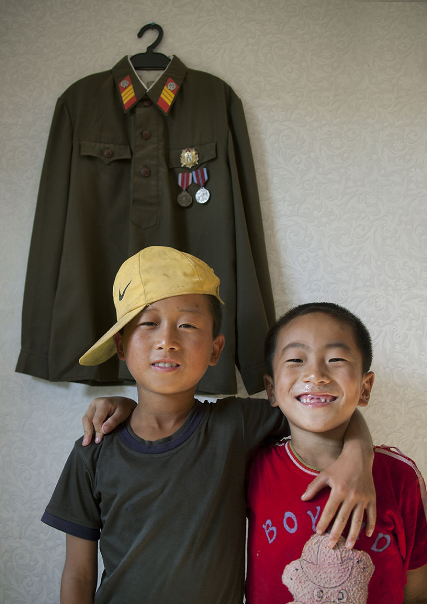 Two Boys Pausing In Front Of Military Uniform, Chonsam, North Korea